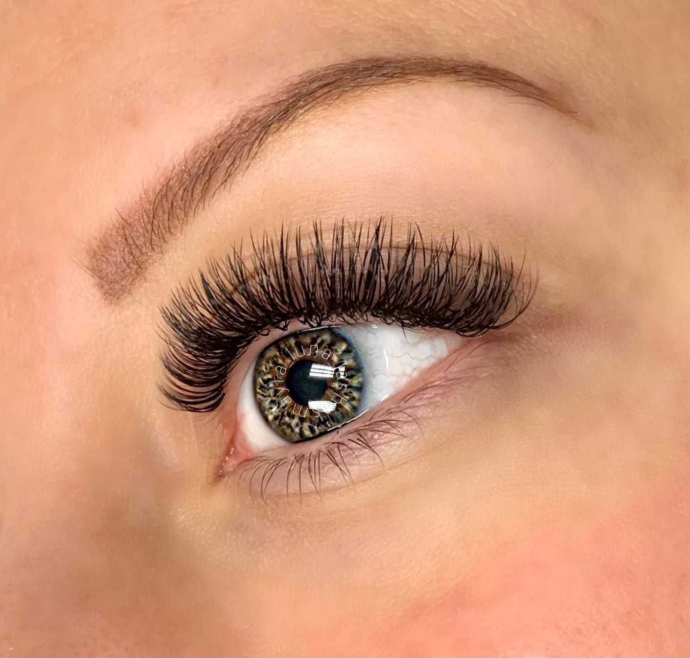 Close-up of a hazel eye with long eyelashes and groomed eyebrow.