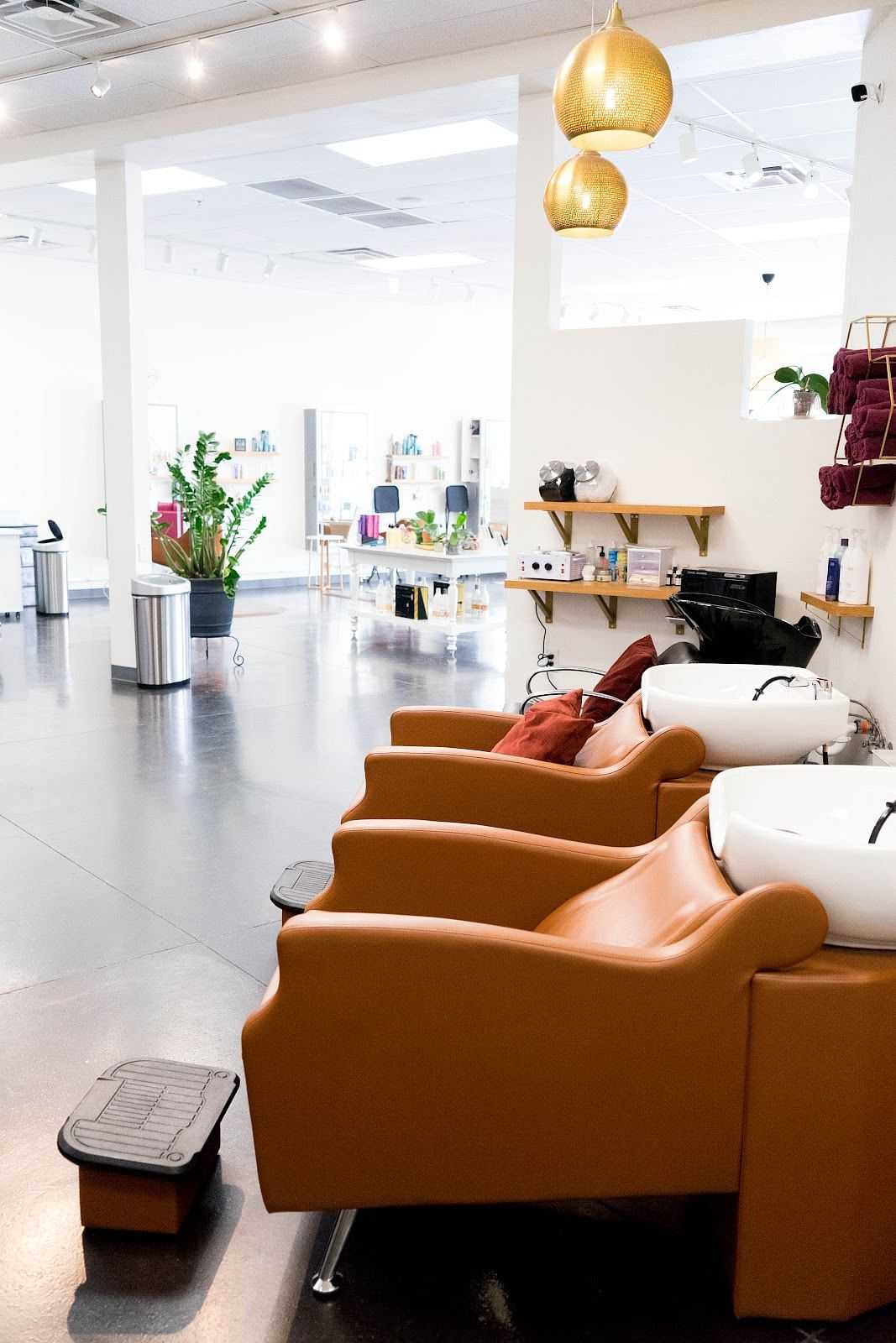 Modern salon interior with orange chairs and hair-washing sinks.